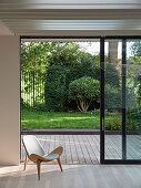 Blick durch offene Schiebetür auf Holzterrasse und Garten, moderne Architektur
