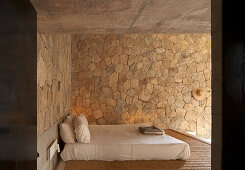 Schlafzimmer mit Doppelbett und Wandverkleidung aus Naturstein