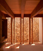 Schlafzimmer mit Holzbalkendecke mit Blick auf Steinmauer