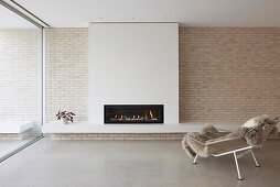 Modern living room design with integrated fireplace and relaxing armchair
