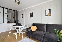 Modern gestalteter Raum mit dunkelgrauer Couch und weißem Esstisch