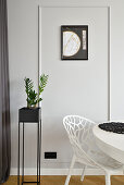 Modern corner with plant, picture on the wall and white chair