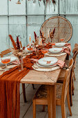 Dining table set with autumn decorations, dried flowers and candles