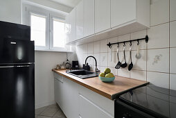 Helle Küche mit Holzarbeitsplatte, schwarzem Herd und schwarzem Kühlschrank