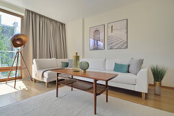 Living room with white sofa, coffee table and tripod floor lamp