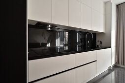 Modern kitchen unit with white fronts and black worktop