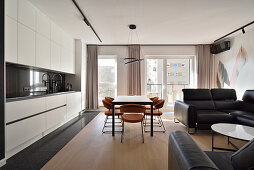 Modern kitchen with integrated dining area and dark leather sofa