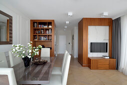 Essbereich mit Glas-Esstisch und modernen Holzmöbeln