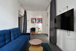 Modernes Wohnzimmer mit blauem Sofa, TV-Bildschirm und Couchtisch