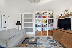 Wohnzimmer mit Bücherregal, TV-Board und gemustertem Teppich