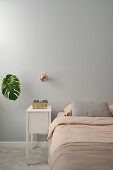 Minimalistisches Schlafzimmer mit cremefarbener Bettwäsche und kupferner Wandlampe