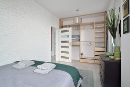 Hell gestaltetes Schlafzimmer mit Regalschrank und weißer Ziegelwand
