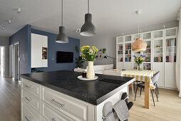 Open-plan kitchen and dining area with marble island and bookshelf in the background