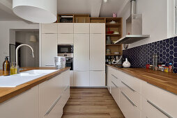 Modern kitchen with white cabinets and dark blue wall tiles in honeycomb pattern