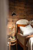 Rustic bedroom with wooden wall, bed, chair and bedside lamp