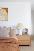 Bedroom with wooden bedside table, lamp and abstract artwork