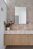 Wooden washbasin with marble top in modern bathroom with wall tiles