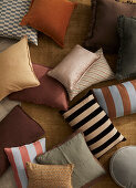 Various decorative cushions with patterns and plain colours on carpet