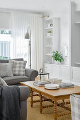 Grey sofa and wooden table in bright living room with bookshelf