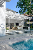 Modern, covered terrace with pool and glass fence