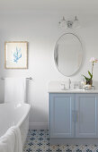 Bright bathroom with light blue vanity unit and mosaic tiled floor