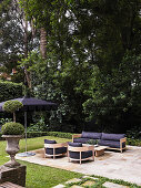 Modern garden lounge area with wooden seating furniture, dark upholstery and parasol