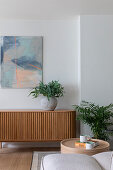 Modern living area with wooden sideboard, artwork and green plants