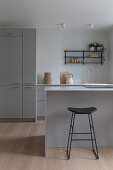 Modern kitchen with grey cabinets and black bar stool