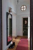 Narrow hallway with wooden floorboards and round skylight