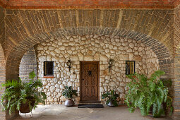 Stone arch, fern and wooden door in colonial style