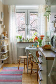 Bright kitchen interior with wooden floor and plants on the windowsill