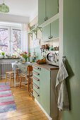 1940s-style kitchen with green cupboards and wooden floor