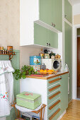 Retro-style fitted kitchen with green cabinets and wooden details