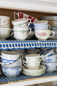 Vintage teacups in a wooden cabinet with a lace border
