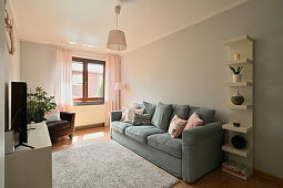 Living room with blue-grey couch and pastel-coloured cushions