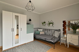 Guest room with metal bed, white wardrobe and light grey wall