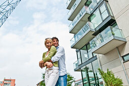 Couple embracing near modern apartment building, HafenCity, Hamburg, Germany