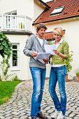 Young couple looking at documents in front of a house, Hamburg, Germany