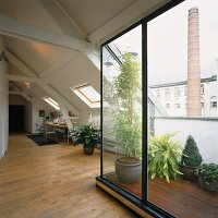 Offener Wohnraum im Dachgeschoss mit Schiebefenster zum Balkon und Nische mit Arbeitsplatz
