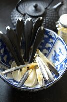 Horn spoons in an oriental porcelain bowl with a teapot in the background