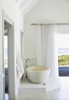 Ein Muschelvorhang und ein Raumtrenner aus Holzstäben im Badezimmer mit