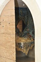 Blick durch Holztür in Badezimmer mit Waschbecken aus Spiegelmosaiksteinen