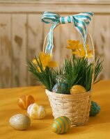 Körbchen gefüllt mit Osterglocken und bunten Ostereiern