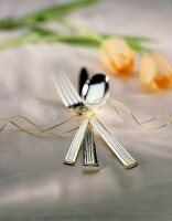 One Set of Silverware tied with Ribbon on Table Cloth with Tulips in Rear