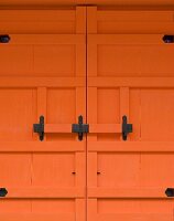 Detail of an orange-painted entrance door with a wrought iron bolt