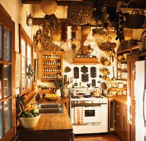 A country house kitchen with baskets, dried chilli peppers and corn cobs hanging from the ceiling, 