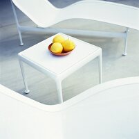 Fruit on a white side table between two loungers