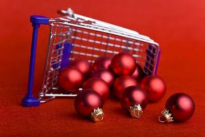 Red Christmas baubles falling out of upset shopping trolley