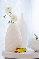White buttercups in a vase with a white knitted cover