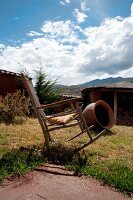 Traditionelles, peruanisches Lehmhaus mit Lehmofen im Garten; im Vordergrund ein alter Schaukelstuhl